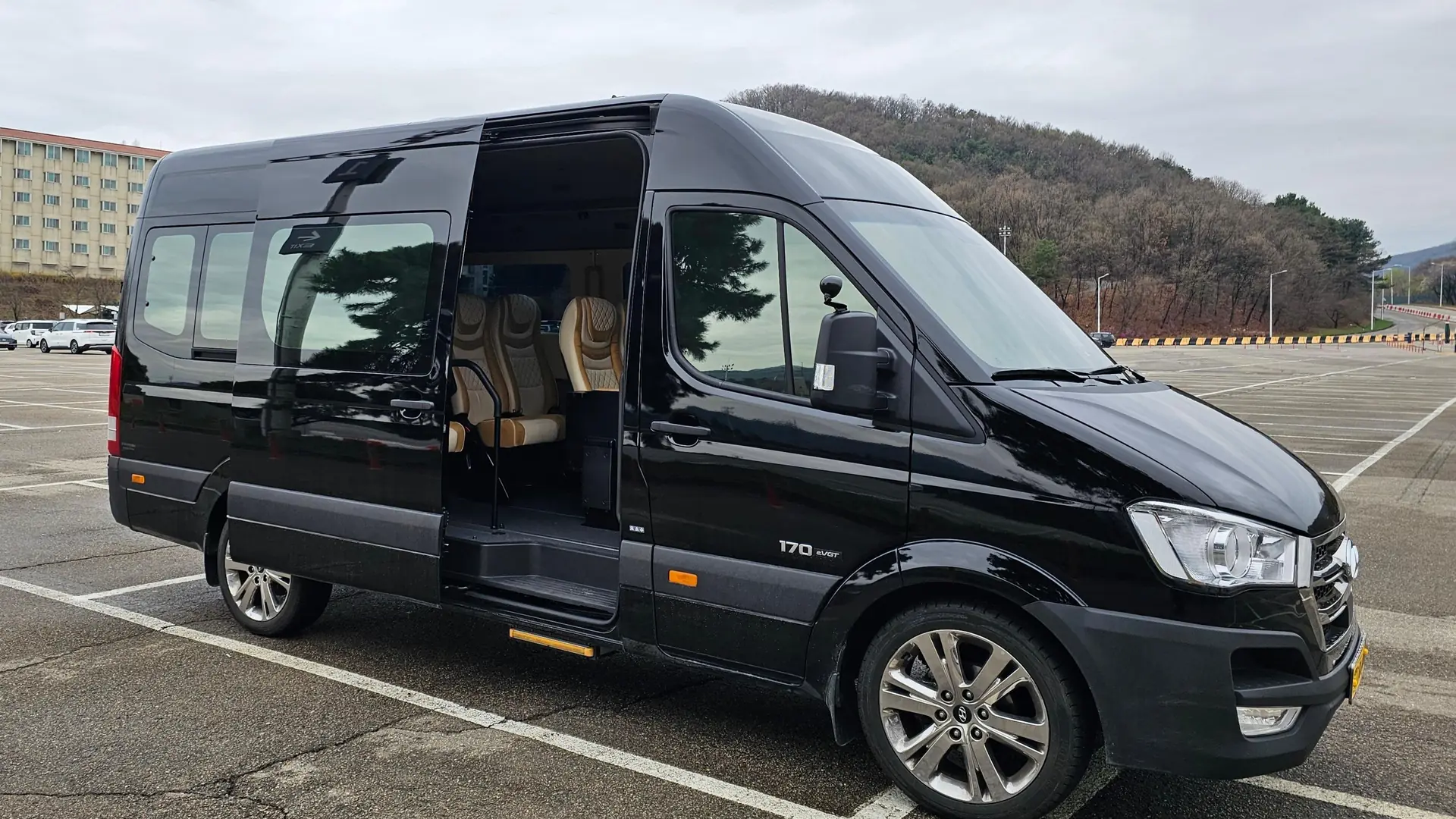 A black 12-seat van in a car park, from the 1-12 passenger Incheon Airport transfer listing