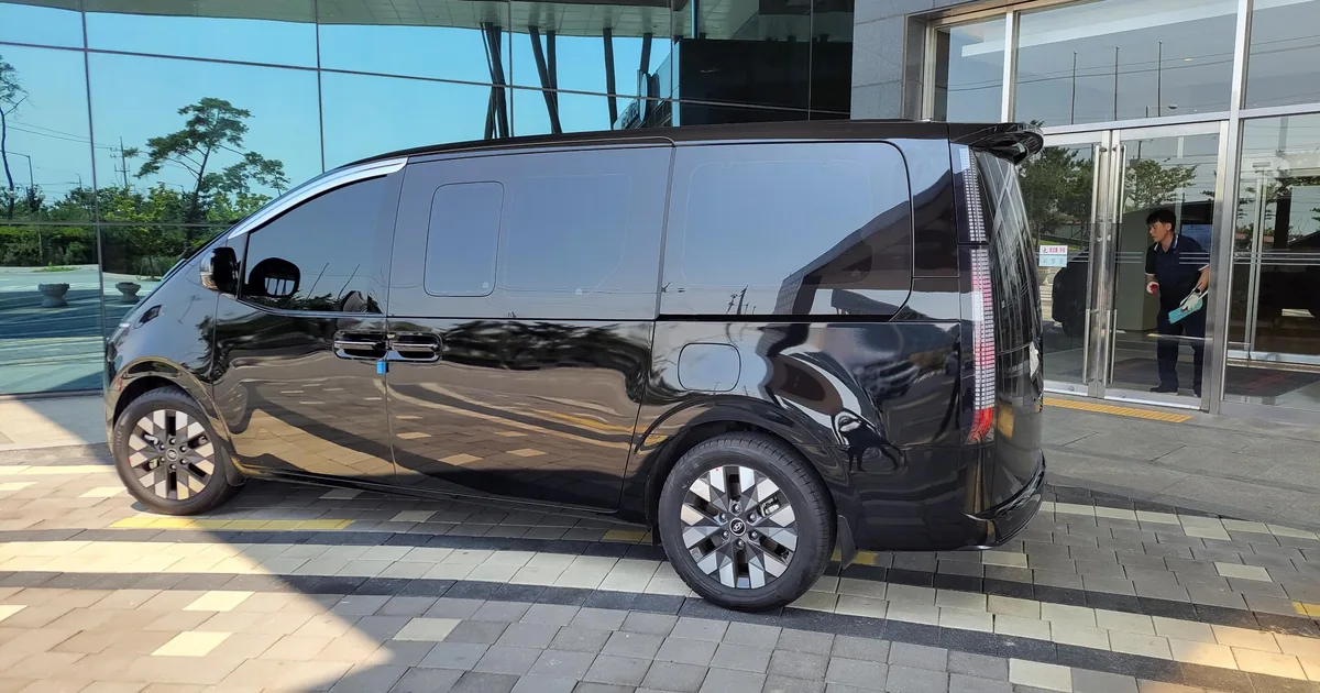 A black private van parked at a hotel entrance before a transfer from Seoul to Busan